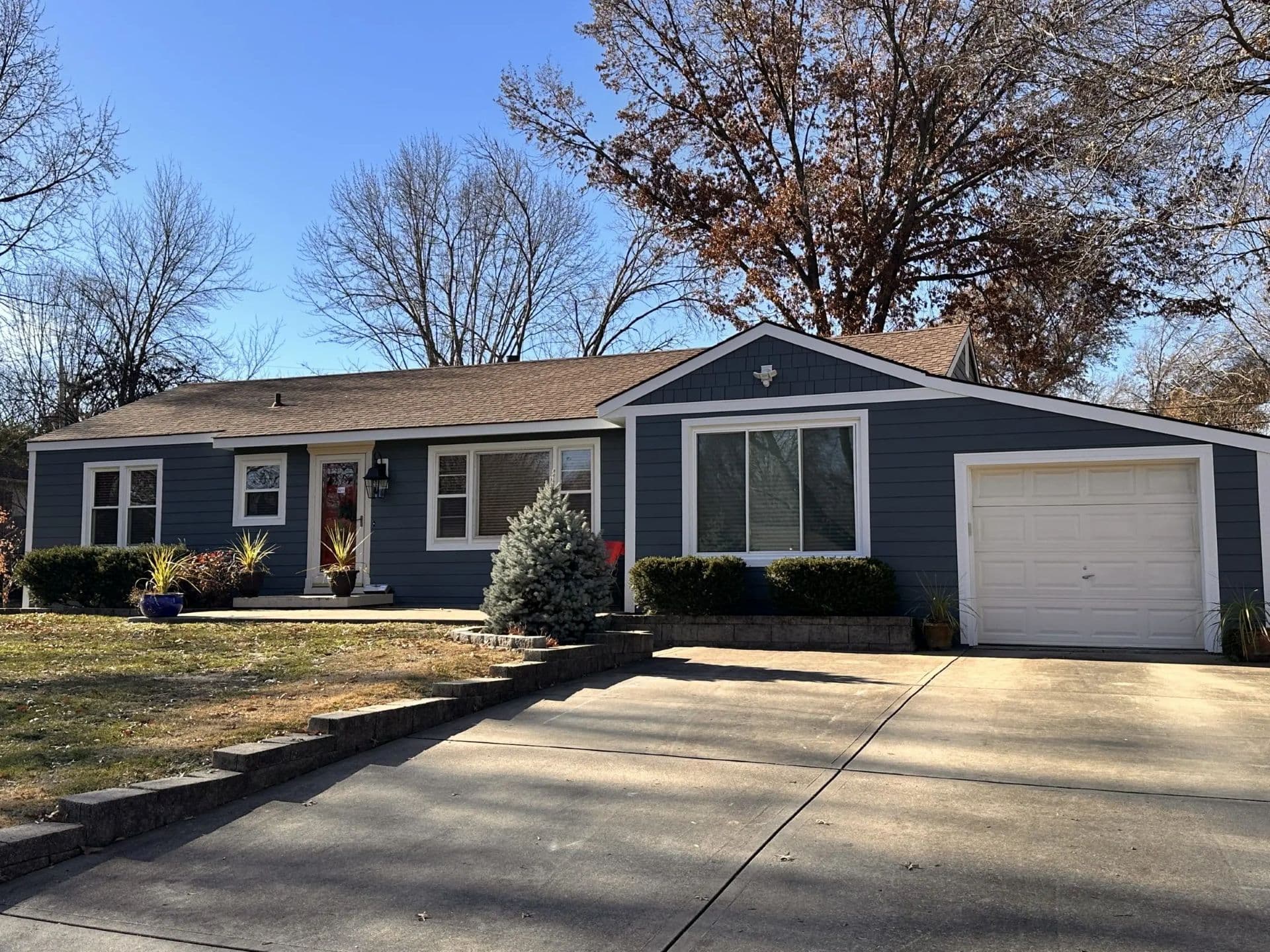 An after photo of a single-story home with new dark blue James Hardie siding and white trim.