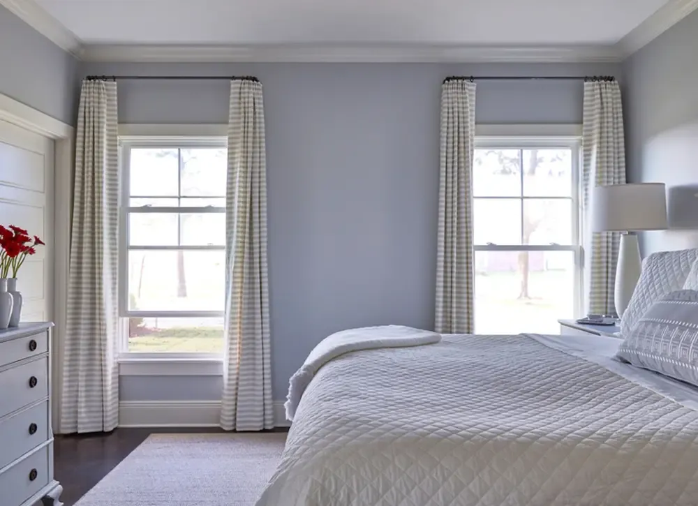 Double-hung windows in a light blue bedroom with white trim.