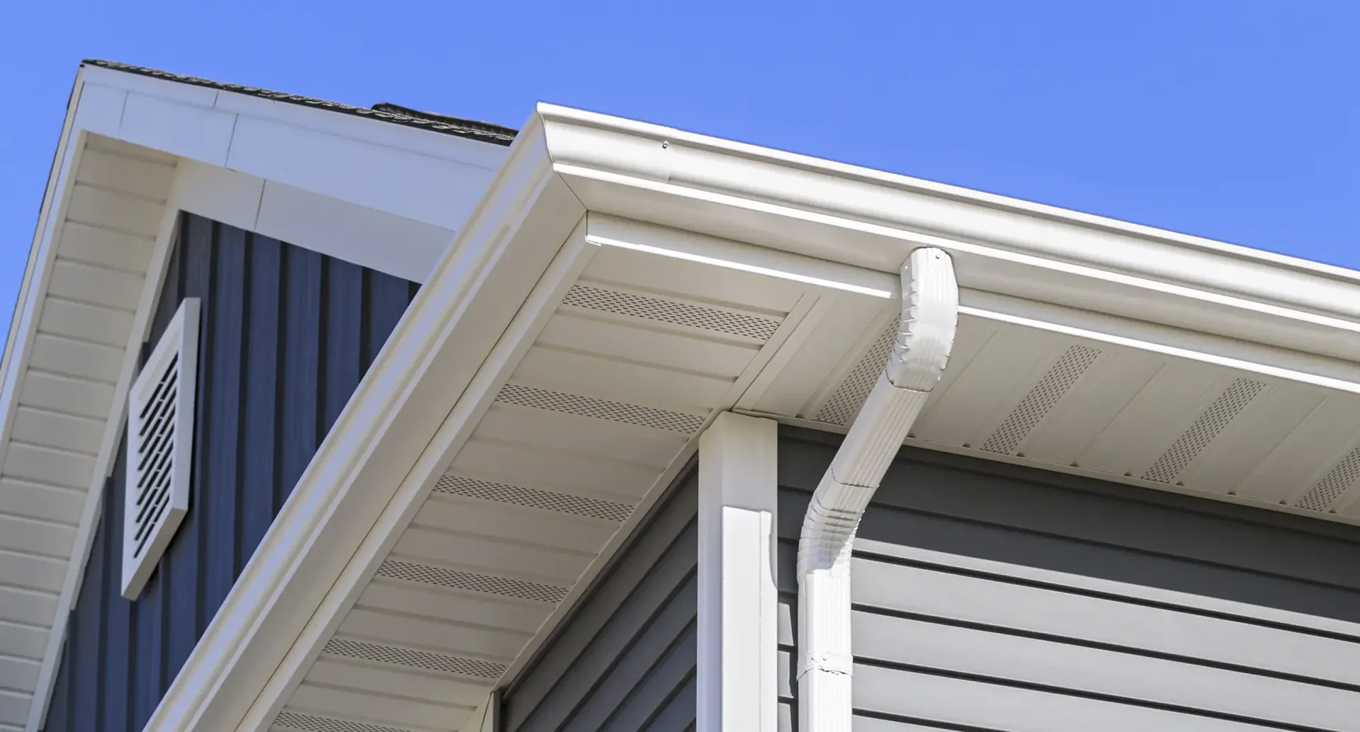 White gutters and downspout on a dark gray house.
