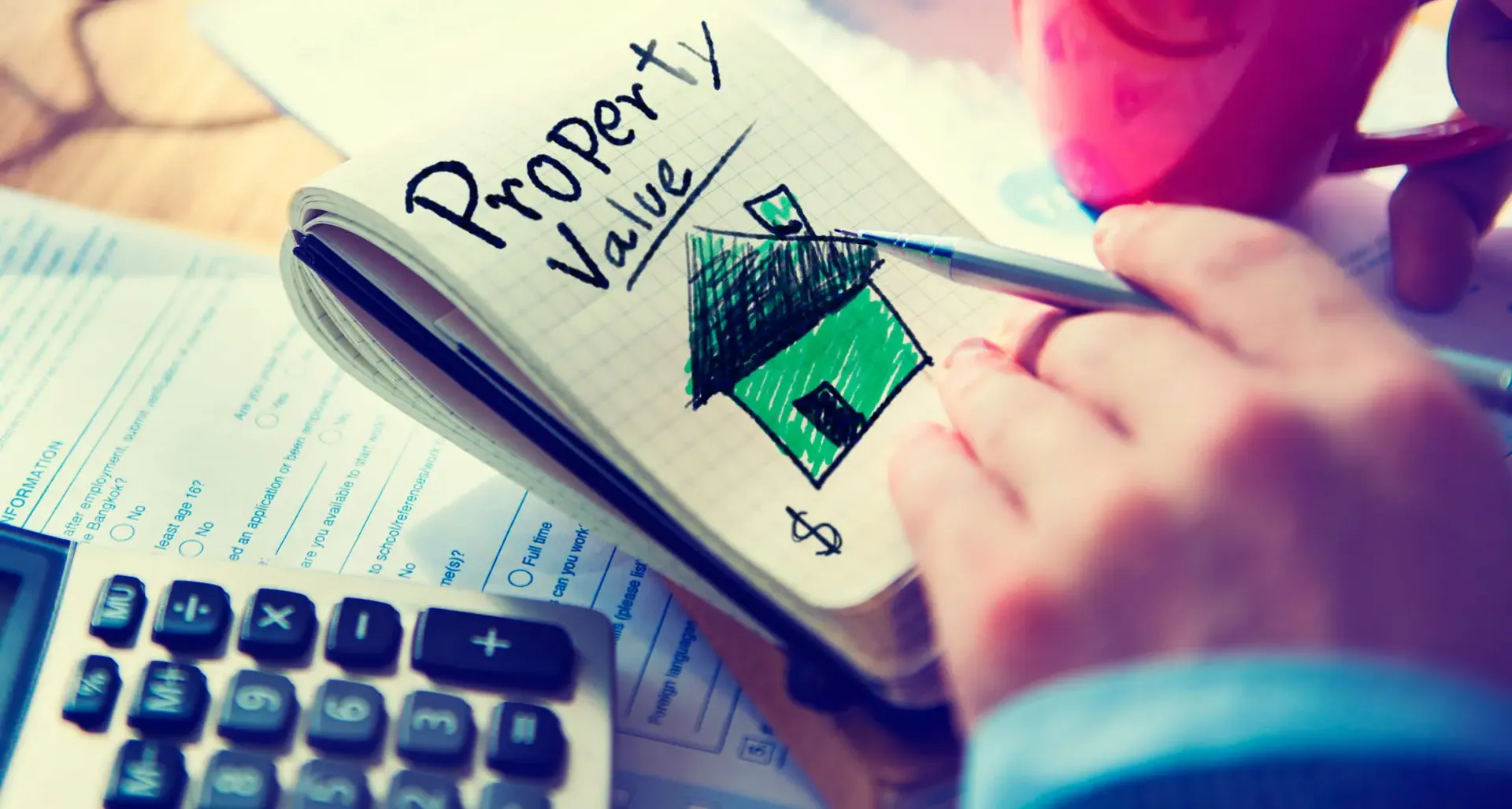 A person draws a cartoon house on a notepad with "Property Value" written on top.