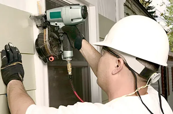 A worker installs James Hardie siding.