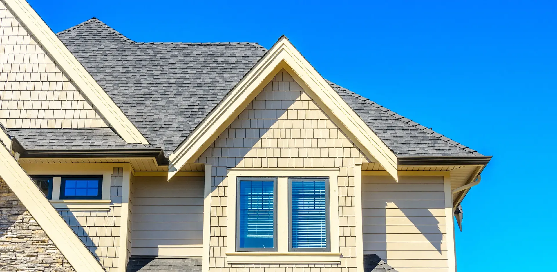 A new gray shingle roof on a light tan house.