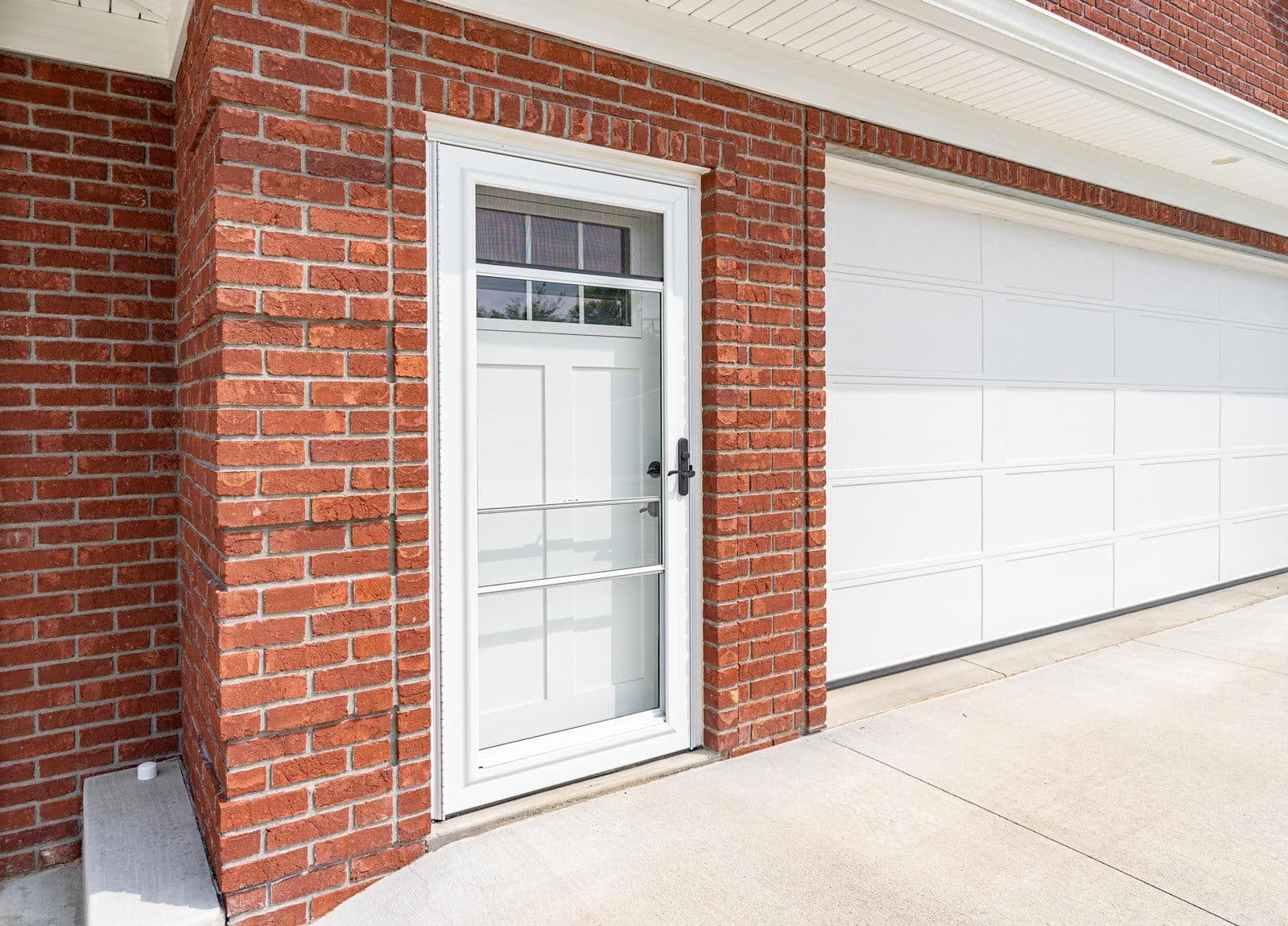 A ProVia Spectrum™ Storm Door in Snow Mist White on a red brick house.